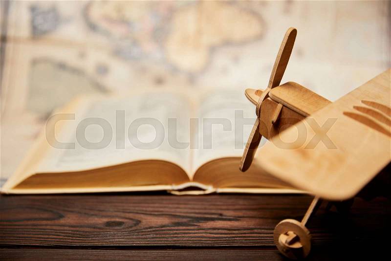 Selective focus of toy plane, book and map on wooden table, stock photo