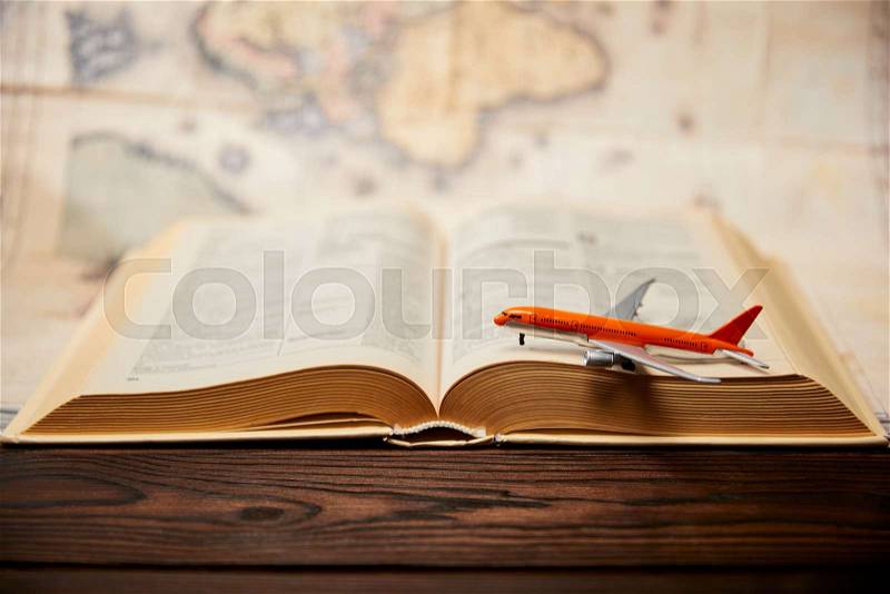 Selective focus of toy plane, book and map on wooden table, stock photo