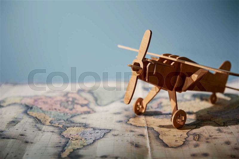 Selective focus of toy plane and map with copy space on blue background , stock photo