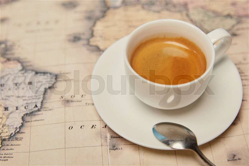 Selective focus of world map and coffee cup with spoon on saucer, stock photo