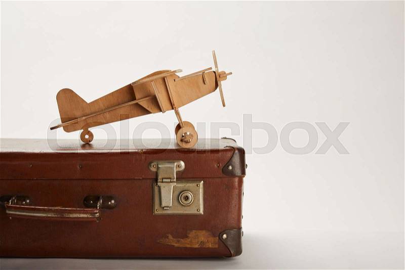 Toy plane and leather suitcase on grey background with copy space , stock photo