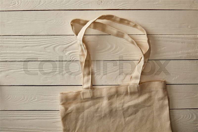 Top view of empty cotton bag on white wooden surface, zero waste concept, stock photo