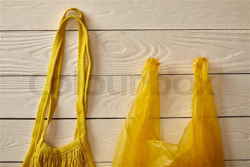 Top view of cotton string bag and plastic bag on white wooden surface, zero waste concept, stock photo