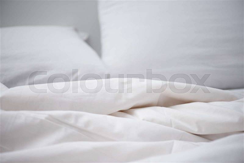 Selective focus of empty bed with white blanket and pillow, stock photo