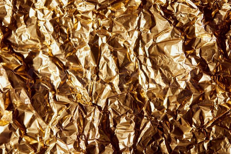 Creased golden foil sheet with twinkles, stock photo
