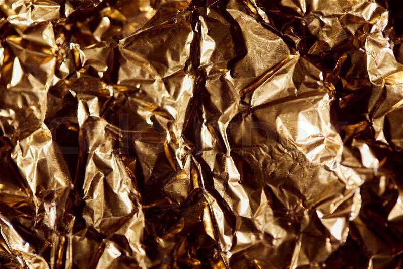 Creased golden foil sheet with twinkles and shadows , stock photo