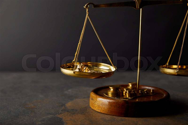 Golden stones on scales on marble surface and black background, stock photo