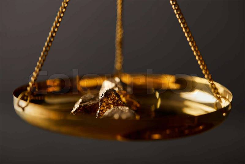 Selective focus of golden stones on scales on dark background, stock photo