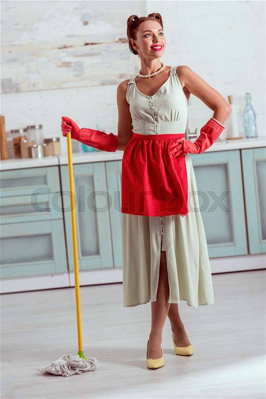 Pretty pin up girl in red apron and red rubber gloves standing with yellow mop, stock photo