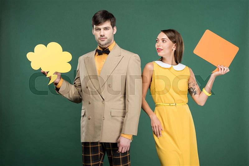 Beautiful couple in vintage clothes holding speech bubble and thought bubble isolated on green, stock photo