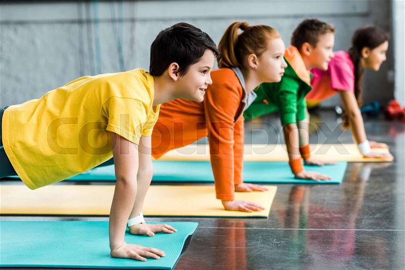 Preteen kids doing plank exercise in gym, stock photo