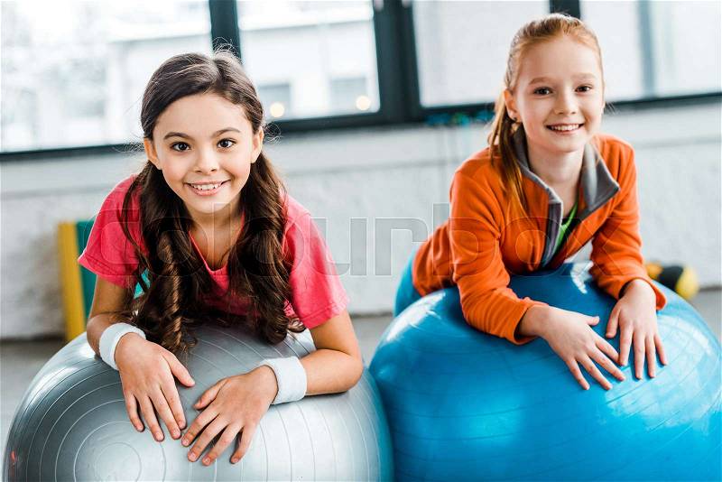 Joyful kids posing on fitness balls with smile, stock photo
