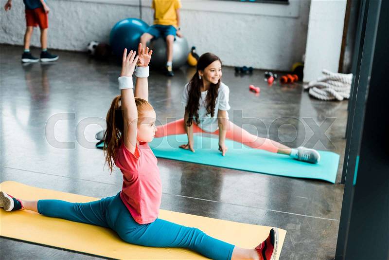 Kids doing twine on fitness mats in gym, stock photo
