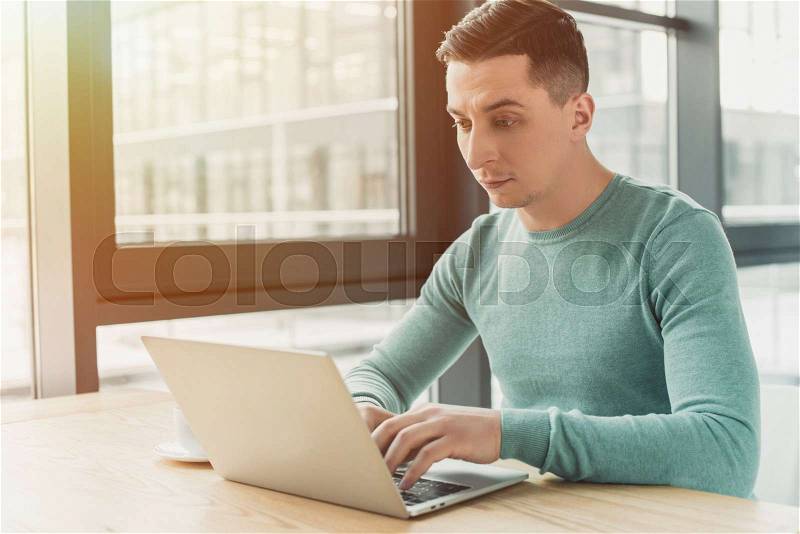 Handsome man typing on laptop while sitting at home , stock photo