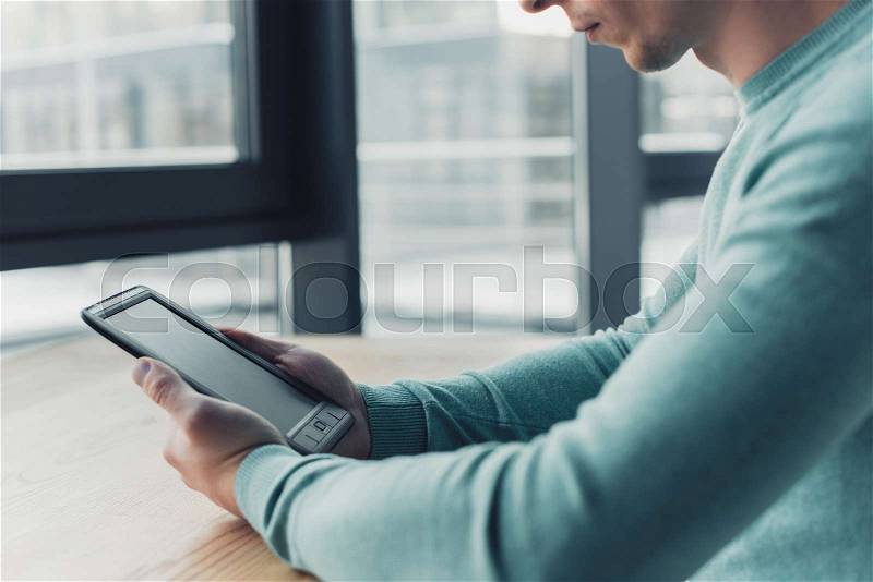 Cropped view of man holding e-book with blank screen, stock photo