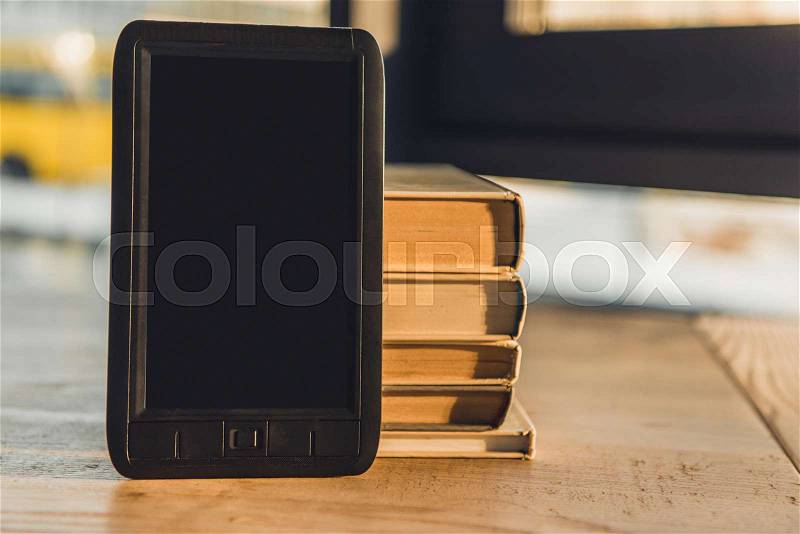 E-book with blank screen near paper books on table, stock photo