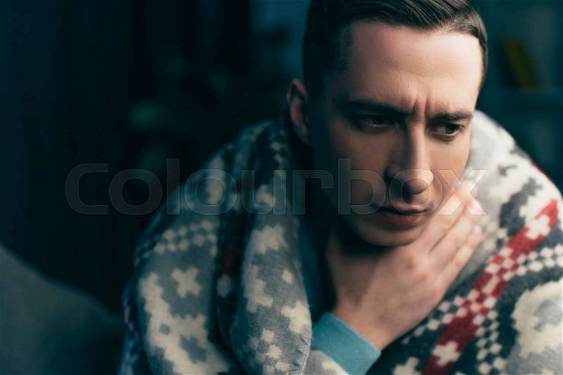 Handsome man wrapped in blanket having sore throat , stock photo