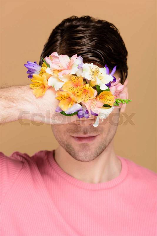 Man covering face with flowers on hand isolated on beige, stock photo