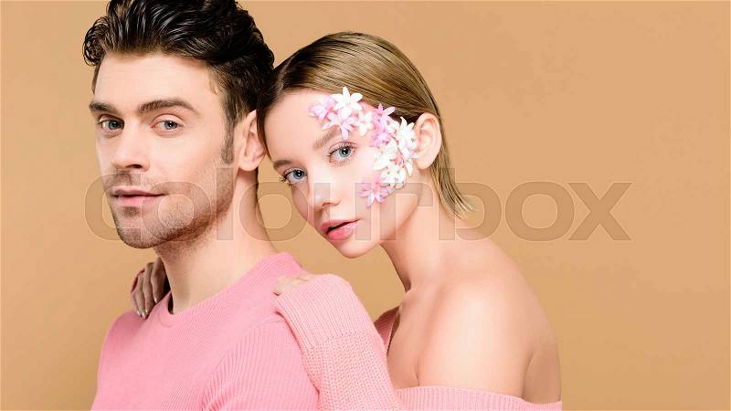 Man and woman with flowers on face isolated on beige , stock photo