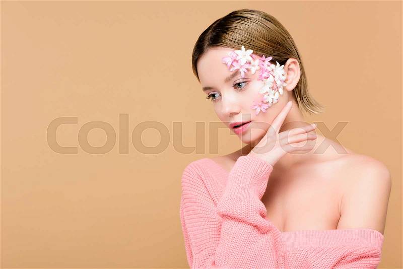 Pensive girl with flowers on face isolated on beige, stock photo