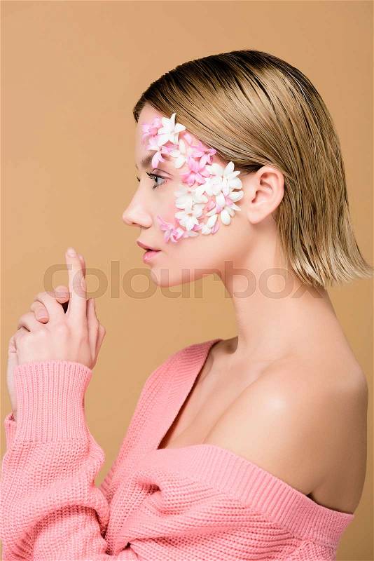 Side view of elegant girl with flowers on face isolated on beige, stock photo