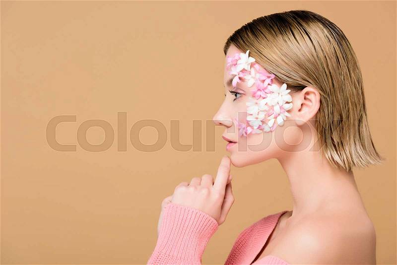 Side view of attractive woman with flowers on face isolated on beige, stock photo