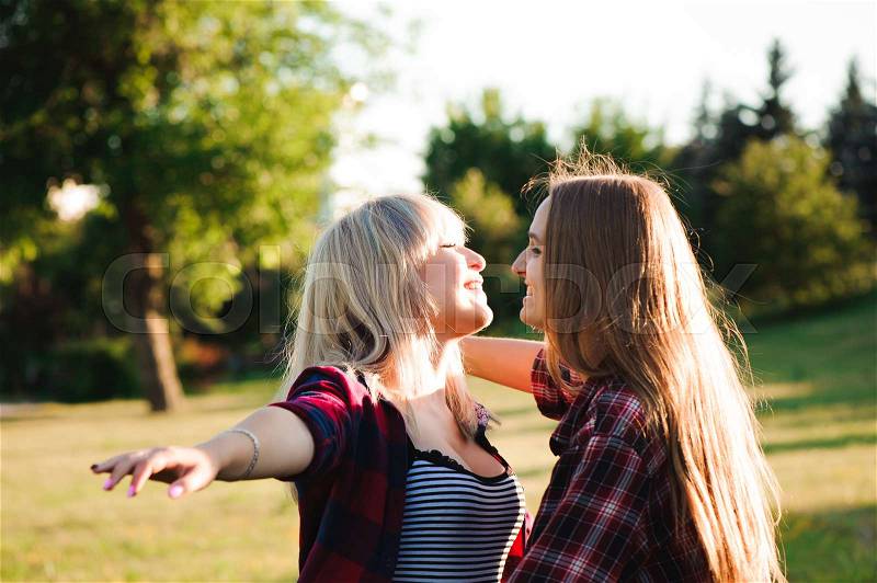 Two girls friends laughing and hugging. Hug and smile outdoor, stock photo