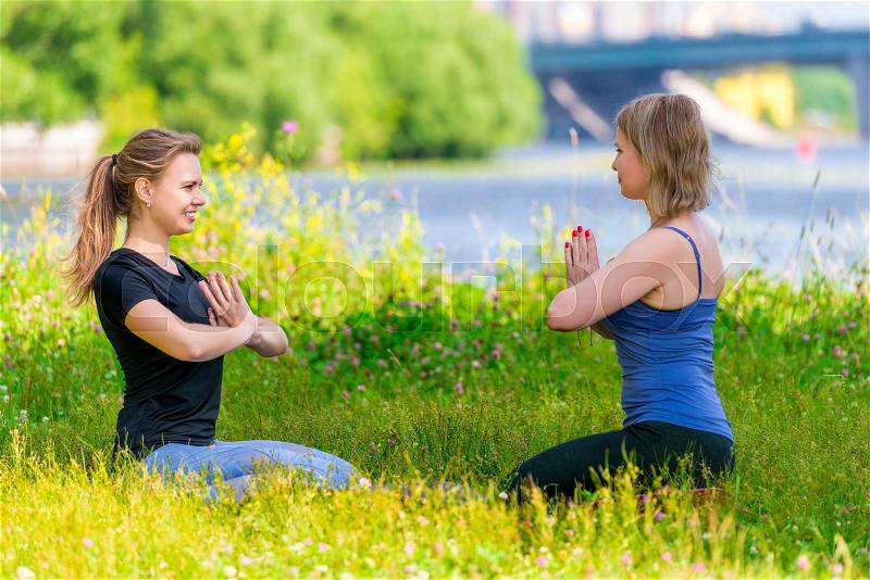 Mature 40 year old woman practices yoga with an experienced trainer in a summer park, stock photo