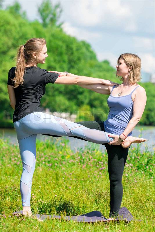 40-year-old woman with an experienced trainer doing yoga individually in the park , stock photo