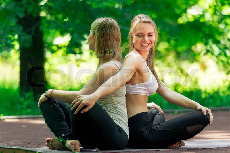 Classes with an individual yoga trainer in the park on a sunny summer day, portrait of active women, stock photo