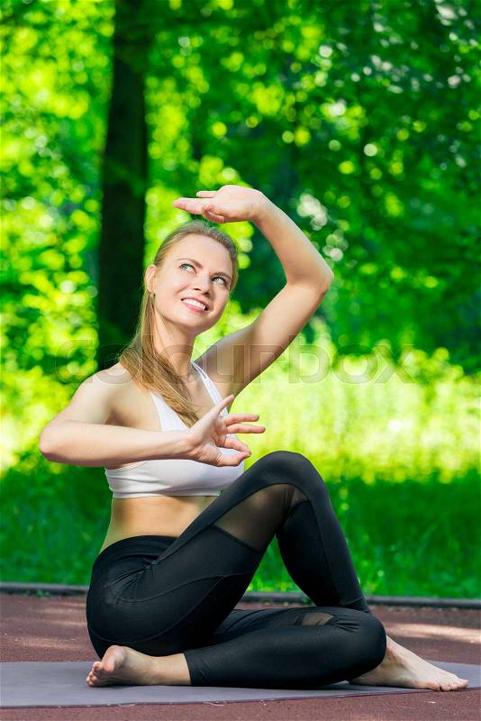 Yoga asanas - pilates and yoga trainer performs exercises in the park, stock photo