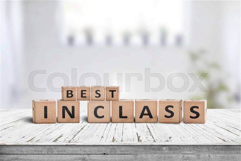 Best in class sign on a wooden table in a bright classroom, stock photo