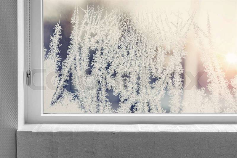 Frosty window seen from the inside with a white windowsill in the winter, stock photo