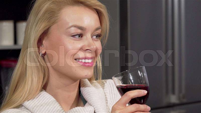 Happy beautiful woman smiling to the camera, enjoying drinking wine at home. Stunning young woman celebrating buying new apartment, sipping wine. Enjoyment, home ..., stock photo