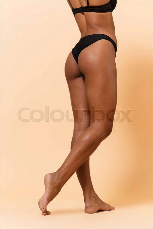 Cropped portrait of amazing woman 20s wearing black lingerie, standing isolated over beige background, stock photo