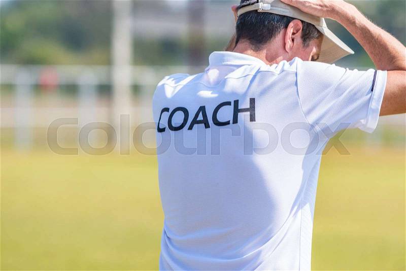 Back view of male sport coach in white COACH shirt at an outdoor sport field putting his hands on his head in disbelief, good for sport or emotion concept, stock photo