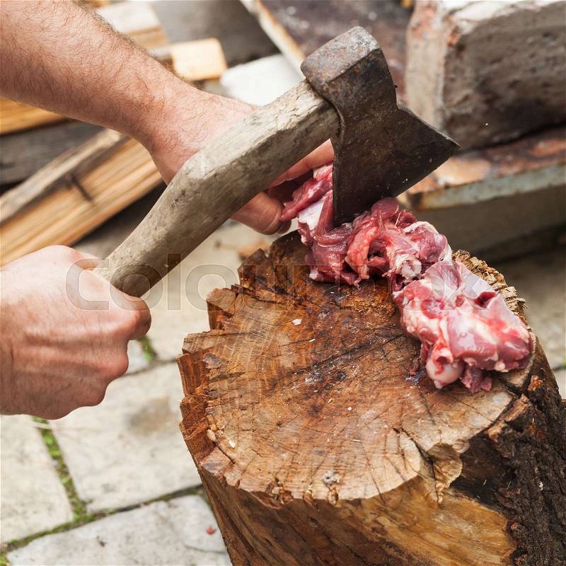 Raw lamb meat cutting on log, cook hands with ax, close-up photo, stock photo