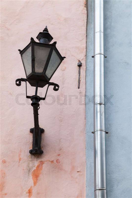 Traditional vintage street light mounted on old house wall in Tallinn, Estonia, stock photo