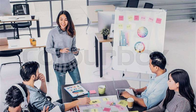 Female Creative director team lead brainstrom branding project with designer team at meeting table.discussion idea in creative office, stock photo