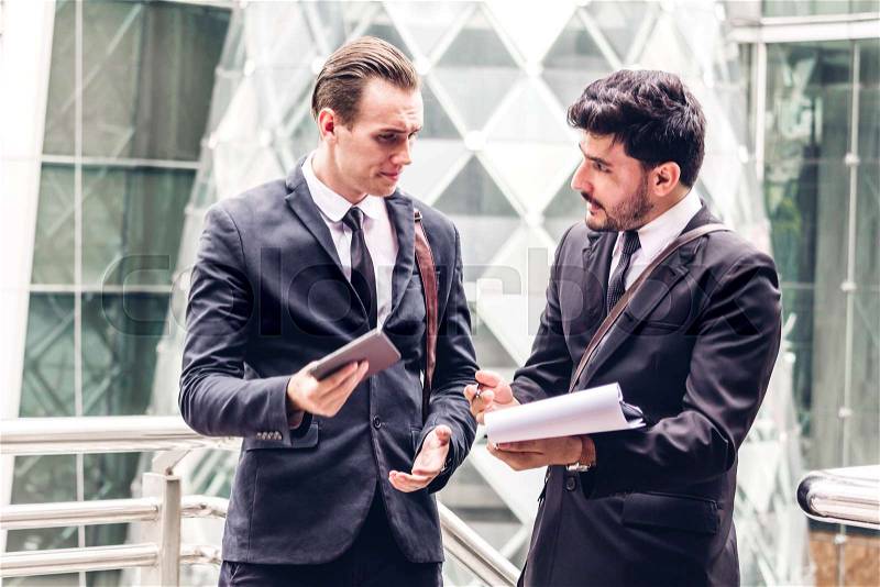 Two smiling businessman coworkers in black suit talking and walking.business people discussing strategy in the modern city, stock photo