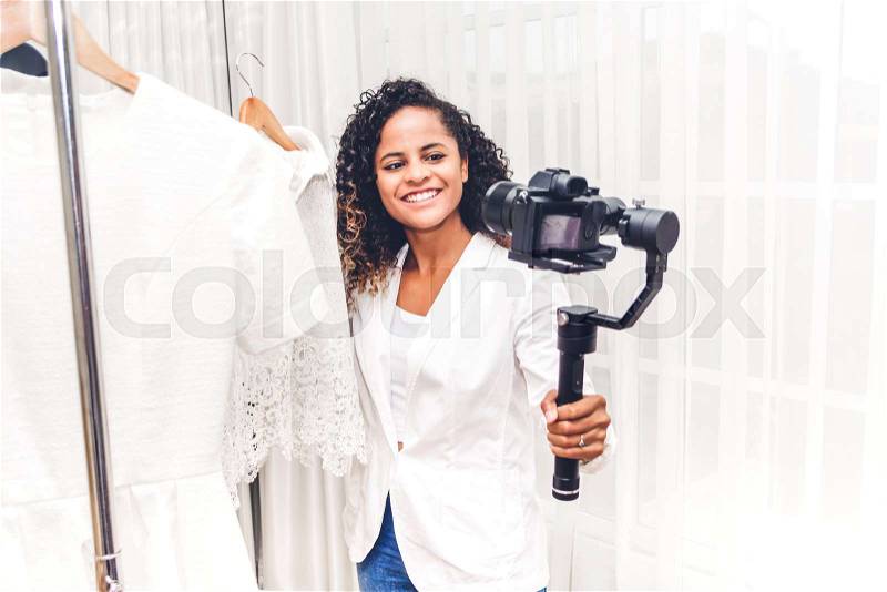 African american woman blogger standing in front of camera recording herself shopping and choosing clothes in a store.fashion shopping and social media concept, stock photo