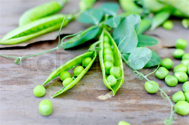 Pods of young green peas and pea on a old rustic wooden background. Dark rustic style, stock photo