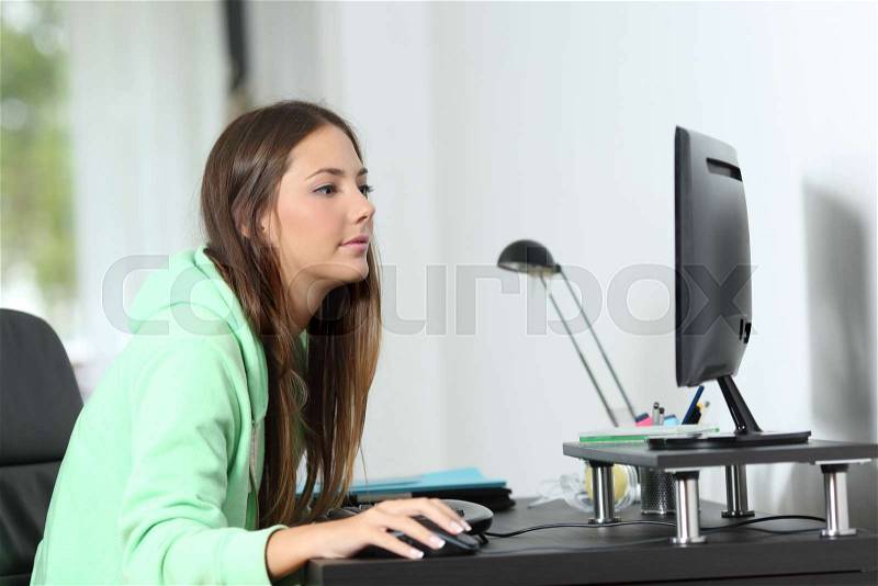 Relaxed woman using a desktop computer sitting in a room at home, stock photo
