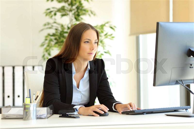 Serious office worker works using a desktop computer, stock photo