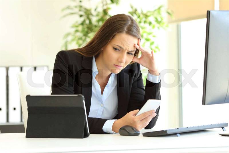 Worried office worker working using multiple devices on a desk, stock photo
