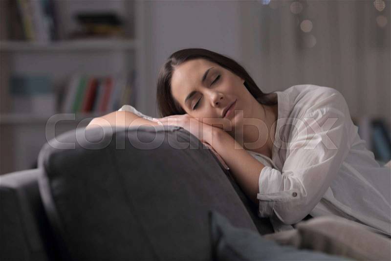 Woman sleeping sitting on a couch in the living room in the night at home, stock photo