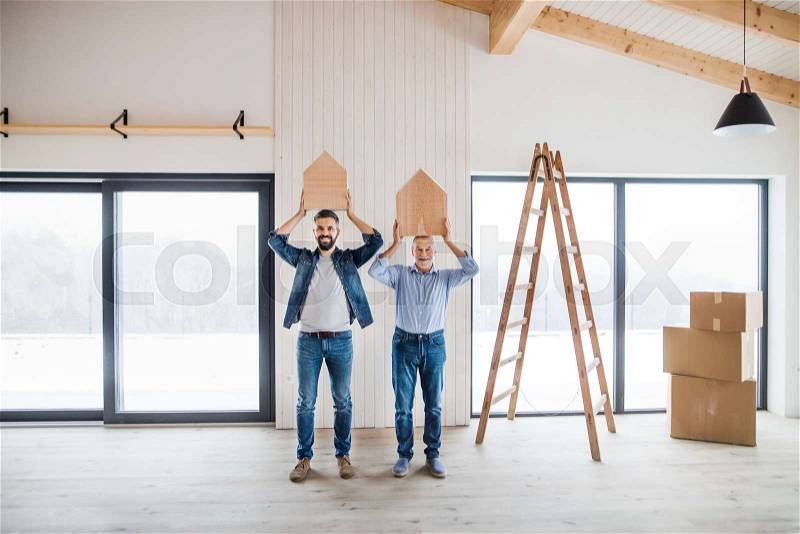 Two men holding small wooden houses on their heads when furnishing new house, a new home concept, stock photo