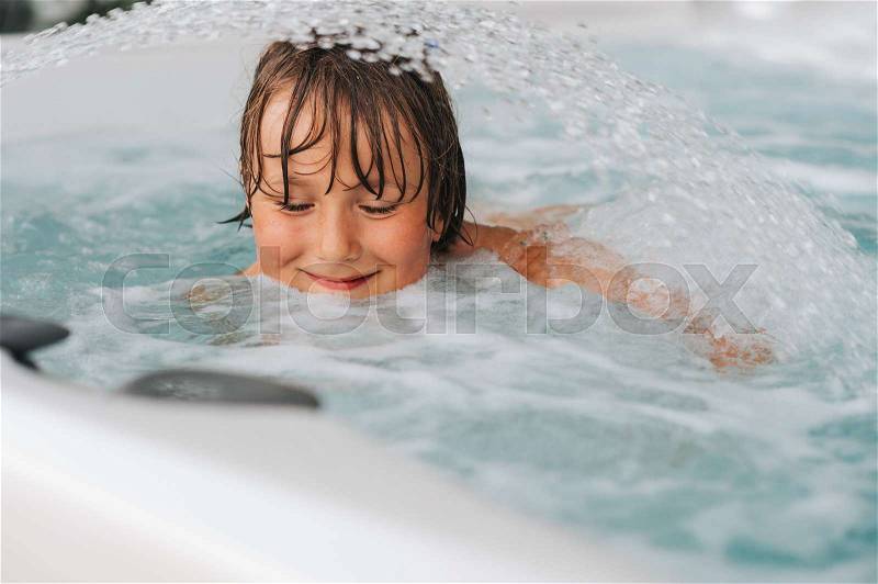 Handsome little boy enjoying warm water in jacuzzi, stock photo