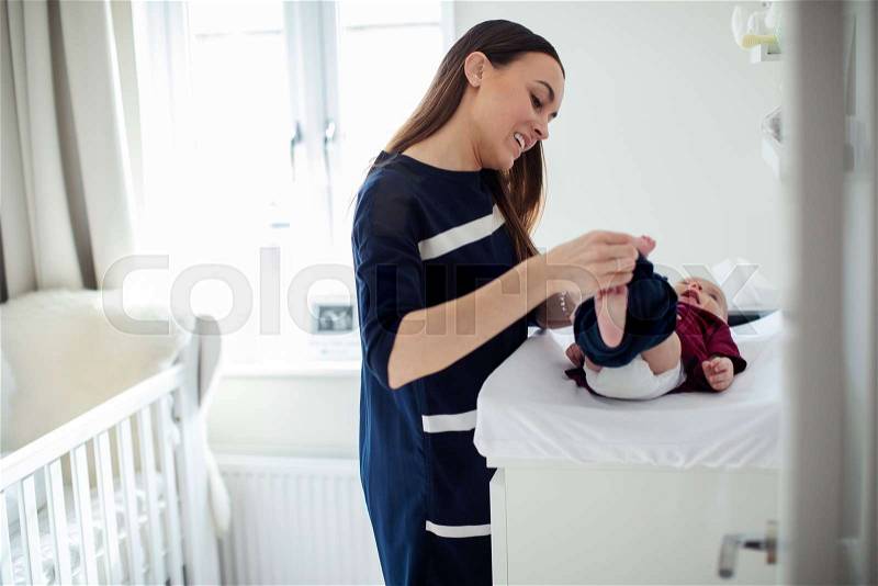 Mother In Nursery At Home Changing Baby Sons Daiper, stock photo
