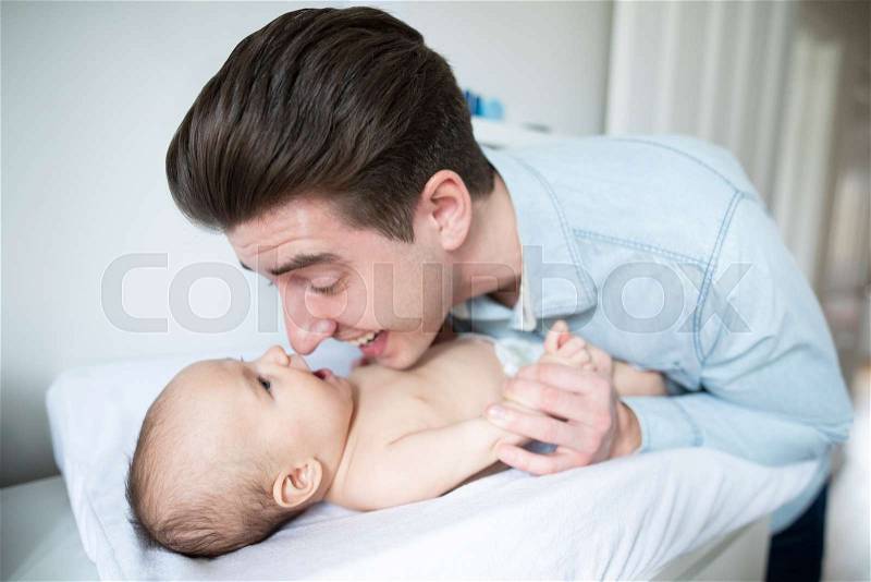 Father In Nursery At Home Changing Baby Sons Daiper, stock photo